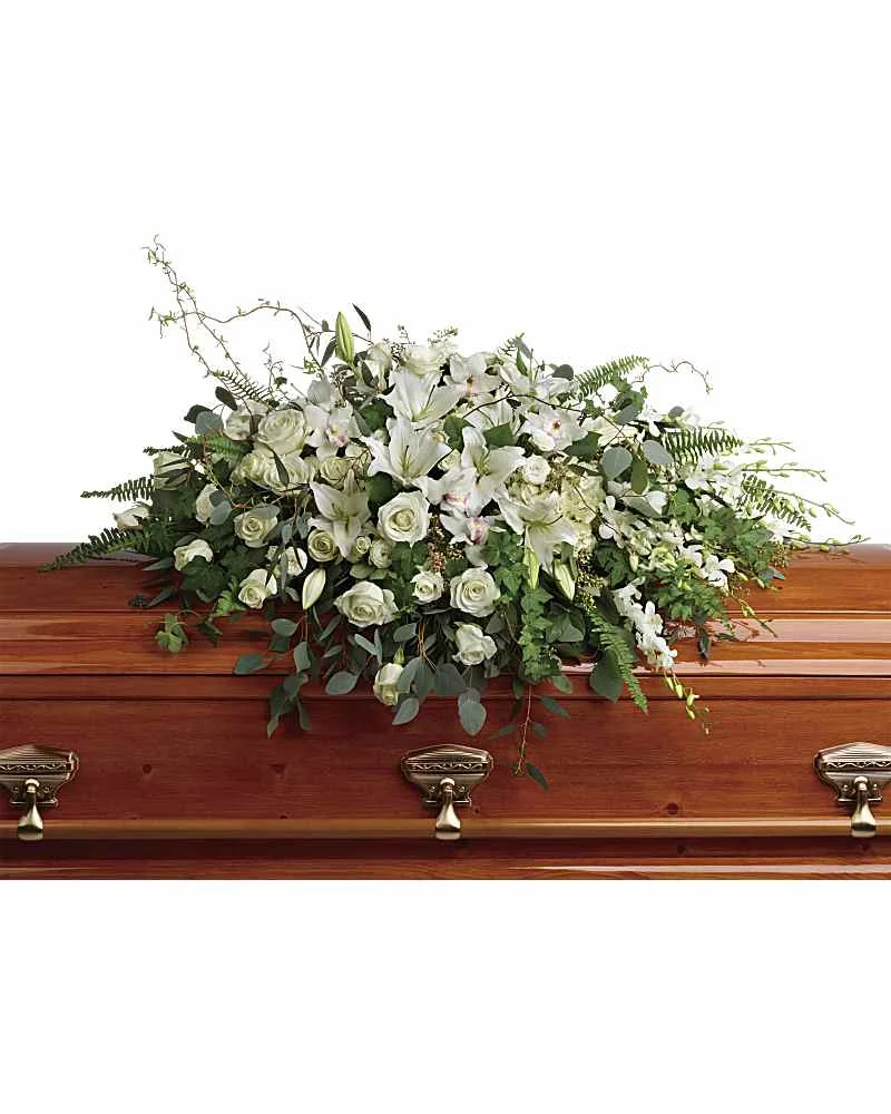Cream white and ivory casket spray arranged across a closed wood casket