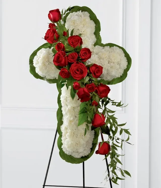 White carnation floral cross with a red rose cascade on a standing easel